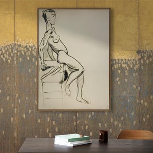 May include: A framed black and white line drawing of a nude figure sitting on a stool. The drawing is on a white background and is framed in a gold frame. The drawing is hanging on a wall with a gold and brown textured wallpaper.