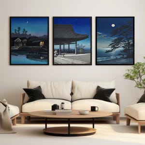 May include: Three framed black and white prints of Japanese scenes with a crescent moon in the sky. The prints are hanging on a white wall above a white couch with black throw pillows.
