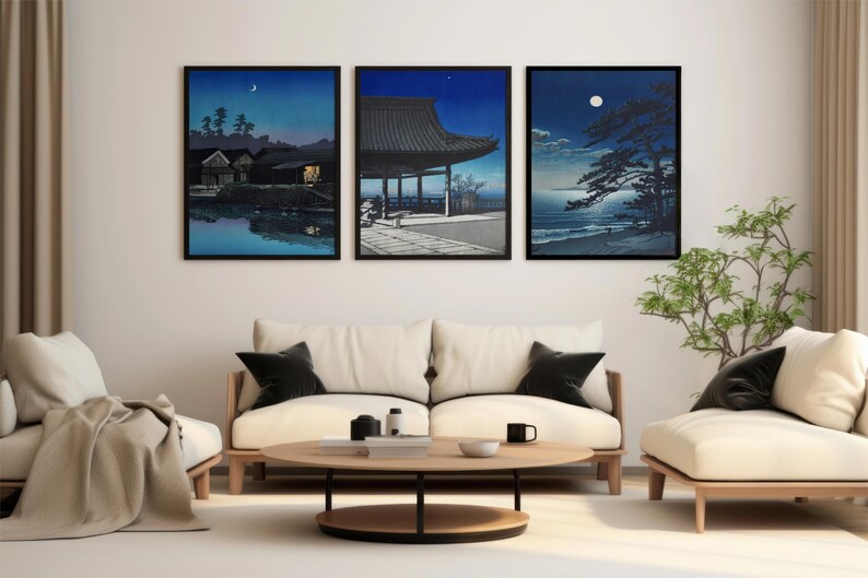May include: Three framed black and white prints of Japanese scenes with a crescent moon in the sky. The prints are hanging on a white wall above a white couch with black throw pillows.