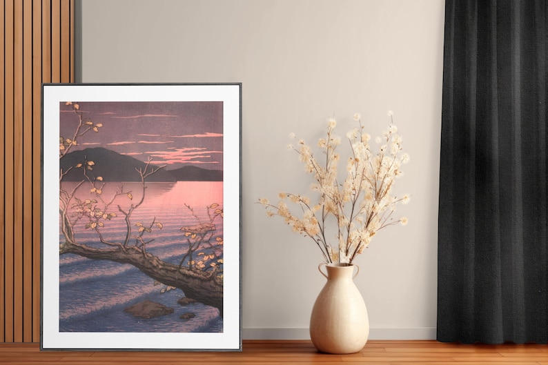 May include: A framed print of a Japanese-style landscape painting depicting a tree branch reaching over a body of water with a mountain in the background. The sky is a soft pink and purple.