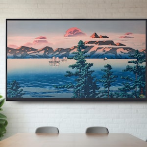 May include: A framed print of a Japanese landscape painting depicting a mountain range, a body of water, and several boats. The sky is a soft pink and blue, and the mountains are a dark blue and green. The water is a deep blue, and the boats are white.