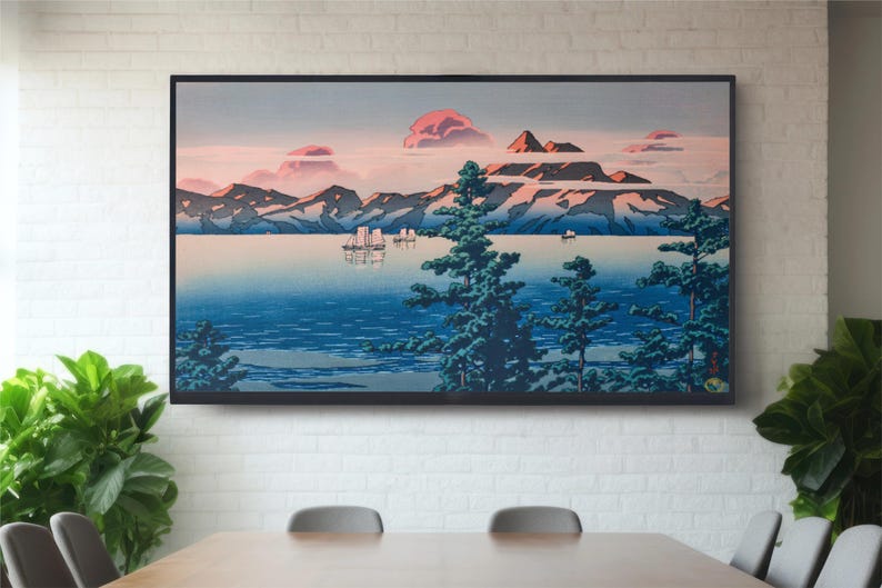 May include: A framed print of a Japanese landscape painting depicting a mountain range, a body of water, and several boats. The sky is a soft pink and blue, and the mountains are a dark blue and green. The water is a deep blue, and the boats are white.