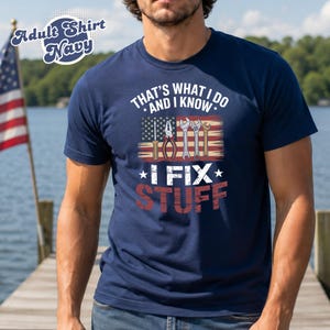 May include: Navy blue t-shirt with the text "THAT'S WHAT I DO AND I KNOW * I FIX STUFF" in white and red. The design includes tools and an American flag. The shirt is labeled "Adult Shirt Navy".