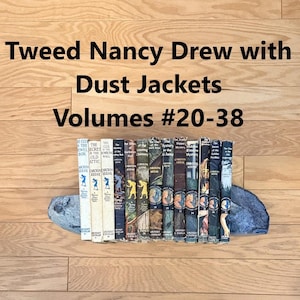 May include: A collection of Nancy Drew mystery books, volumes 20 through 38, featuring illustrated dust jackets with varied color spines. The books are arranged in a row, supported by two grey, textured, rock-like bookends on a wooden surface.