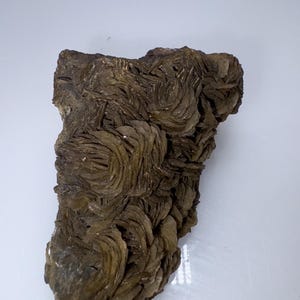 Könnte beinhalten: Eine große, braune, felsartige Formation aus Selenitkristallen. Die Kristalle sind in einem wirbelnden Rosettenmuster angeordnet.