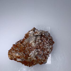 May include: A rough, brown rock with white crystals embedded in it. The rock has a natural, earthy look.