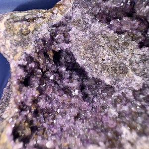 May include: Close-up of a purple amethyst geode with a rough exterior and a sparkling, crystalline interior.