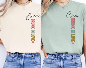 May include: Two women wearing t-shirts with the text "Bride Drunk in Love" and "Crew Drunk in Love". The shirts are in ivory and bay colours.