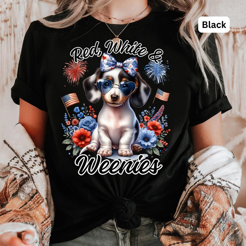 May include: Black t-shirt featuring a dachshund wearing heart-shaped sunglasses and a bow, surrounded by red, white, and blue flowers and fireworks. The text reads "Red, White & Weenies".