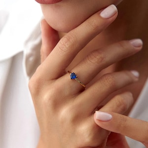 May include: A gold ring with a blue heart-shaped gemstone.
