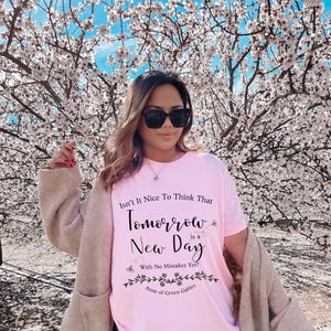 May include: A pink t-shirt with a black graphic that reads "Isn't It Nice To Think That Tomorrow is a New Day With No Mistakes Yet?" and "Anne of Green Gables".