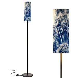 May include: A floor lamp with a cylindrical lampshade featuring a blue and white tropical design. The lamp has a dark metal pole and base, with a foot switch for easy operation. The lampshade showcases palm trees and clock gears.