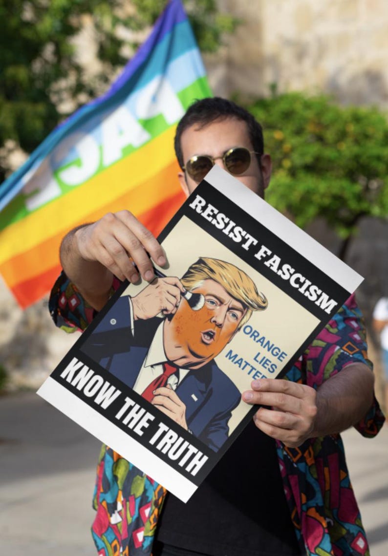 May include: A poster with the text "RESIST FASCISM" and "KNOW THE TRUTH" features a caricature of a man with orange skin. The words "ORANGE LIES MATTER" are also visible. A rainbow flag is in the background.