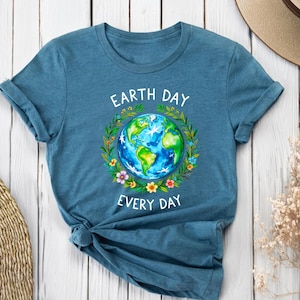 Puede incluir: Una camiseta azul turquesa con un gr&aacute;fico blanco de la Tierra rodeada de flores y el texto "Earth Day Every Day".