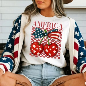 Camiseta con cereza americana, camiseta gráfica del 4 de julio, camiseta con lazo patriótico, camiseta de verano de EE. UU., camiseta con la bandera de EE. UU., camiseta coqueta, camiseta para mujer de EE. UU.