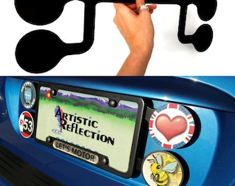 May include: A black quad holder for car badges, held by a hand. The holder is shown mounted on a blue car with a license plate frame and various badges. The text "ARTISTIC REFLECTION" and "LET'S MOTOR" are visible.