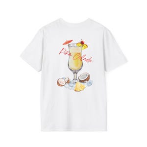 Könnte beinhalten: Weißes T-Shirt mit einer Aquarellillustration eines Piña Colada Cocktails. Das Design umfasst ein Cocktailglas, einen roten Schirm, eine Kirsche, Ananas, Eis und Kokosnüsse. Die Worte "Piña Colada" sind in roter Schrift geschrieben.