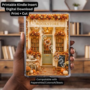 May include: A clear Kindle case containing a printable insert featuring a bookstore storefront decorated for autumn with orange and yellow foliage, pumpkins, a wreath, and a chalkboard sign that reads Fall is my favourite chapter.