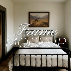Puede incluir: Una cama con una cabecera y un edredón de lino blanco, sobre un marco de metal negro. La cama está en un dormitorio con una impresión enmarcada de un ciervo en un campo sobre la cabecera. El texto "Frame Mockup" está superpuesto a la imagen.