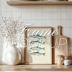 Puede incluir: Una impresión artística enmarcada con ilustraciones de acuarela de peces en tonos azules y amarillos. La obra de arte se exhibe sobre una superficie de madera, junto a un jarrón blanco con flores secas, una tabla de cortar de madera y frascos con tapas. El texto "Frame Mock Up" está superpuesto.