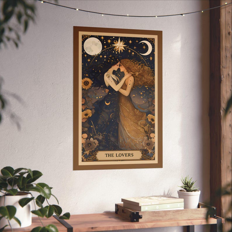 The Lovers Sapphic Art Print, Lesbian Wedding Gift, Whimsigoth Decor, Queer Art Poster. A beautifully illustrated sapphic art print that blends whimsigoth decor, celestial romance, and vintage aesthetics. Featuring two lovers entwined beneath a dreamy night sky, this piece radiates warmth, connection, and cosmic harmony. Displayed tacked/taped on a wall above a modern wood shelf with books and plants on it and string lights above.