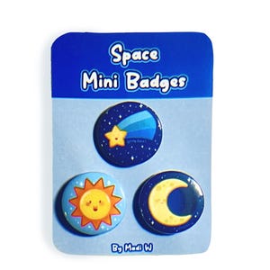 May include: A set of three space-themed mini badges on a blue backing card. The badges feature a shooting star, a smiling sun, and a crescent moon. The card reads "Space Mini Badges" and "By Madi W."