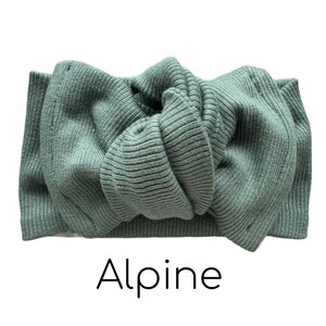 Pode incluir: Uma faixa de cabe&ccedil;a de malha verde s&aacute;lvia com um design de n&oacute;. A faixa de cabe&ccedil;a &eacute; feita de um tecido de malha canelada e apresenta a palavra "Alpine" em uma fonte preta moderna na parte inferior.