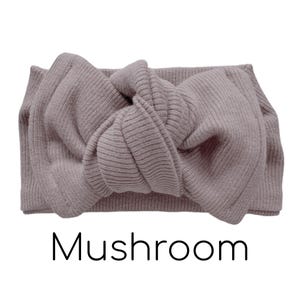 Pode incluir: Faixa de cabelo canelada na cor cogumelo com um la&ccedil;o atado no centro. A palavra "Mushroom" est&aacute; impressa em preto abaixo. Um acess&oacute;rio de cabelo elegante.