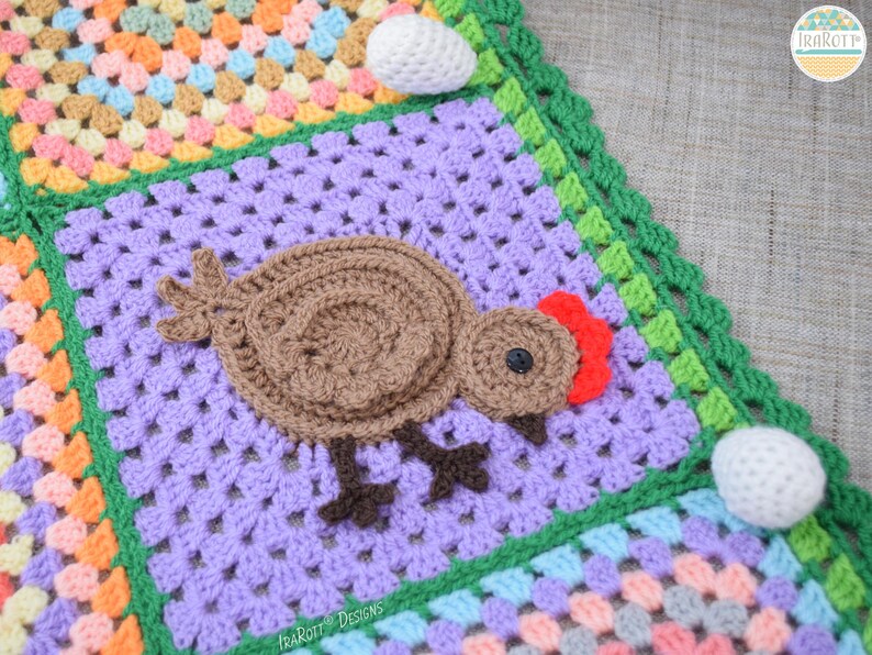 Pode incluir: Uma manta de croch&ecirc; com um quadrado roxo que apresenta um frango de croch&ecirc; marrom com uma crista vermelha. A manta &eacute; feita com uma variedade de cores e texturas, incluindo verde, rosa e amarelo.