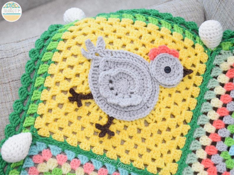 Pode incluir: Um cobertor de croch&ecirc; com um design de patchwork colorido. O cobertor apresenta uma aplica&ccedil;&atilde;o de pintinho de croch&ecirc; cinza com bico e pernas marrons. O cobertor &eacute; enfeitado com uma borda de croch&ecirc; verde.