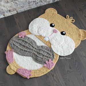 May include: A crocheted hamster rug with a gray belly, pink paws, and a yellow head. The rug is made with soft yarn and is perfect for a child's room.