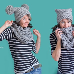 以下が含まれることがあります： 2人の女性がグレーのクロシェハットとスカーフを着用しています。左側の帽子にはポンポンが付いています。両方の女性はストライプのシャツとジーンズを着用しています。