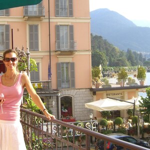 a woman standing on a balcony next to a building