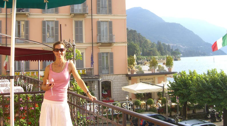 a woman standing on a balcony next to a building