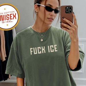 Anti-ICE protest shirt that says “FUCK ICE” in bold white text on a vintage Pepper color t-shirt. Graphic is clean and strong with all-caps block letters centered on chest. Designed for protests and progressive voices. Available in unisex sizing S–4XL. Soft ring-spun cotton, fast shipping, and machine washable.