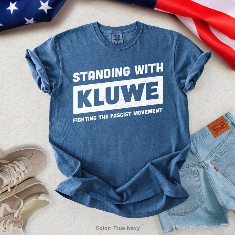 May include: A blue t-shirt with white text that reads "Standing with Kluwe Fighting the Fascist Movement".