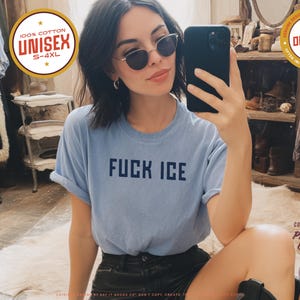 May include: Light blue unisex t-shirt with the text "FUCK ICE" in navy blue. The shirt is made of 100% cotton and is available in sizes S-4XL. The image also includes a round gold sticker that says "ORIGINAL ONLY FOUND HERE".