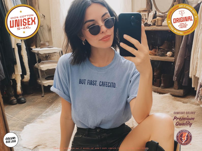 K&ouml;nnte beinhalten: Ein hellblaues Unisex-T-Shirt mit dem Text "BUT FIRST. CAFECITO." wird gezeigt. Das Shirt besteht aus 100 % Baumwolle und ist in den Gr&ouml;&szlig;en S-4XL erh&auml;ltlich. Das Shirt hat die Farbe Blue Jean.