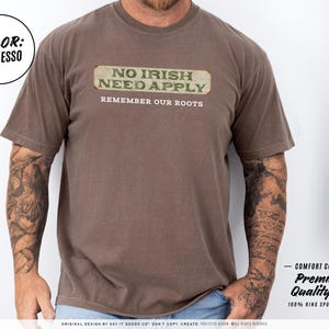 Graphic tee featuring the phrase “No Irish Need Apply” with “Remember Our Roots” printed beneath in bold white lettering. A vintage, historical design on a Comfort Colors® cotton shirt, perfect for Irish Americans, history buffs, educators, and those honoring immigrant heritage. Ideal for St. Patrick’s Day, cultural pride, or anti-discrimination messaging. Available in unisex sizing.