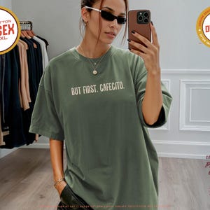 K&ouml;nnte beinhalten: Ein unisex T-Shirt in Moosgr&uuml;n mit dem wei&szlig;en Schriftzug "BUT FIRST. CAFECITO.". Das Shirt besteht aus 100% Baumwolle und ist in den Gr&ouml;&szlig;en S-4XL erh&auml;ltlich. Es geh&ouml;rt zur Comfort Colors Premium Quality Kollektion.