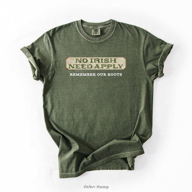 Graphic tee featuring the phrase “No Irish Need Apply” with “Remember Our Roots” printed beneath in bold white lettering. A vintage, historical design on a Comfort Colors® cotton shirt, perfect for Irish Americans, history buffs, educators, and those honoring immigrant heritage. Ideal for St. Patrick’s Day, cultural pride, or anti-discrimination messaging. Available in unisex sizing.