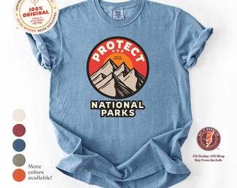 May include: A blue t-shirt with a graphic design of a mountain range with a red sun and the text "Protect Our National Parks 1872 & Beyond".