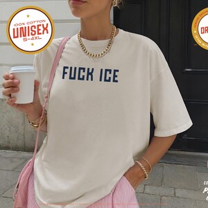Anti-ICE protest shirt that says “FUCK ICE” in bold white text on a vintage Pepper color t-shirt. Graphic is clean and strong with all-caps block letters centered on chest. Designed for protests and progressive voices. Available in unisex sizing S–4XL. Soft ring-spun cotton, fast shipping, and machine washable.
