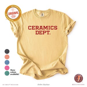 以下が含まれることがあります： バター色の半袖Tシャツで、胸元にダークレッドのブロック体で「CERAMICS DEPT.」という文字がプリントされています。クルーネックの標準的なフィット感で、左上隅に円形のロゴがあしらわれています。