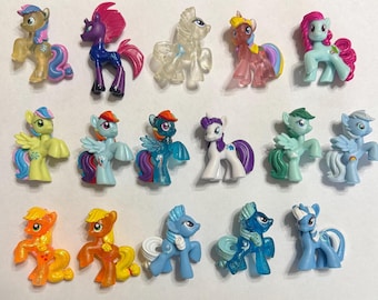 Puede incluir: Una colección de 17 pequeñas figuras de pony de plástico en varios colores y poses. Los ponis tienen pelo, alas y colas de diferentes colores. Algunos ponis tienen símbolos en sus flancos.