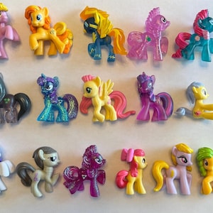 May include: A collection of colorful toy ponies in various poses. The ponies are made of plastic and feature different colors, including pink, yellow, blue, purple, and green. Some have wings, and all have unique designs.