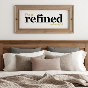 May include: A framed wooden sign with the words "She is refined" in black and gold lettering, with the Bible verse "malachi 3:3" below. The sign hangs above a bed with pillows and a blanket.