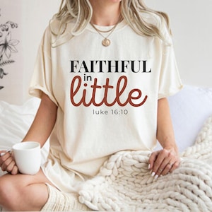 Peut inclure: T-shirt crème avec l'inscription "FAITHFUL in little" en noir et bordeaux, avec "luke 16:10" en dessous. Le t-shirt est de coupe ample.