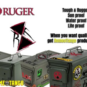 Puede incluir: Varias cajas de munici&oacute;n met&aacute;licas de color verde oliva con asas negras y varias pegatinas de marcas. La imagen incluye el logotipo de Ruger y el texto "Tough & Rugged, Sun proof, Water proof, Life proof". Tambi&eacute;n es visible el texto "When you want quality get RomeoTango products".