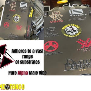 Puede incluir: Una funda para tableta verde oliva cubierta con varias pegatinas de marcas, incluyendo "Vudu", "Romeo Tango" y "Daniel Defense". La funda tiene una correa negra con la palabra "SUPREME" y el texto "Se adhiere a una amplia gama de sustratos. Pure Alpha Male Vibe."